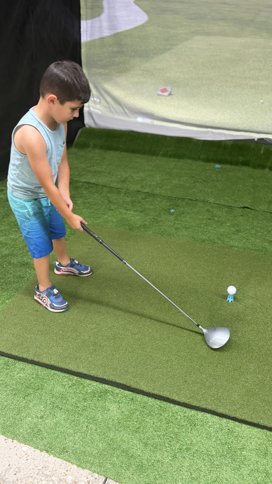 Young child teeing off on the turf at a Riverside Fairways mobile golf simulator party