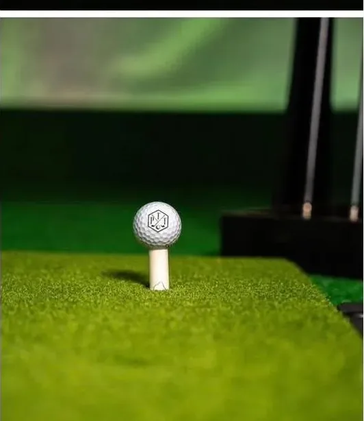 Close-up of a golf ball on a tee on the hitting mat of a mobile golf simulator