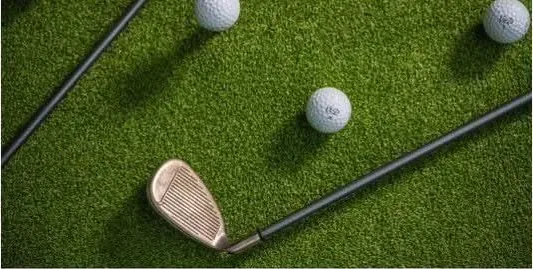 Golf clubs and balls laid out on the turf of a mobile golf simulator