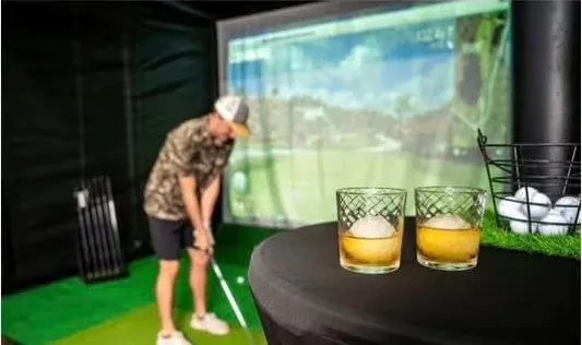 Guest playing a mobile golf simulator indoors with drinks set out nearby