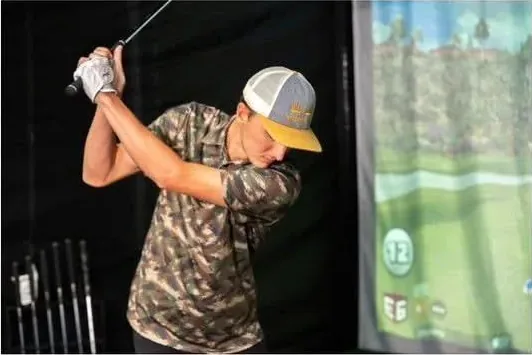 Guest taking a swing on a mobile golf simulator at an indoor event