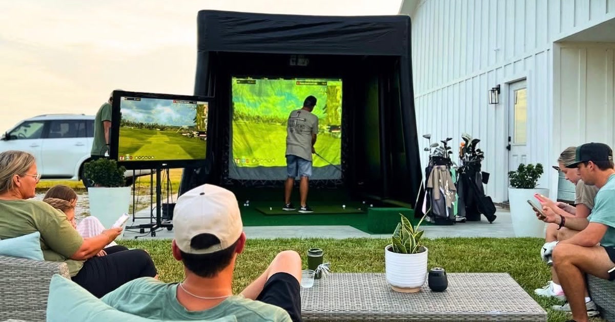 Riverside Fairways mobile golf simulator set up in a backyard at dusk with guests watching