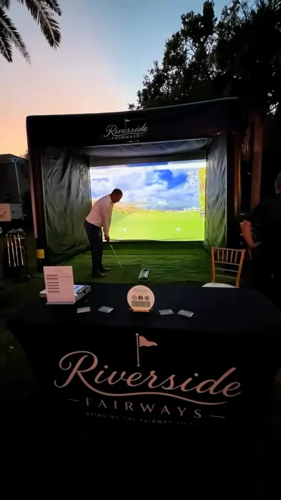 Guest taking a swing on the Riverside Fairways mobile golf simulator at Toast to the Coast in Pass Christian, Mississippi